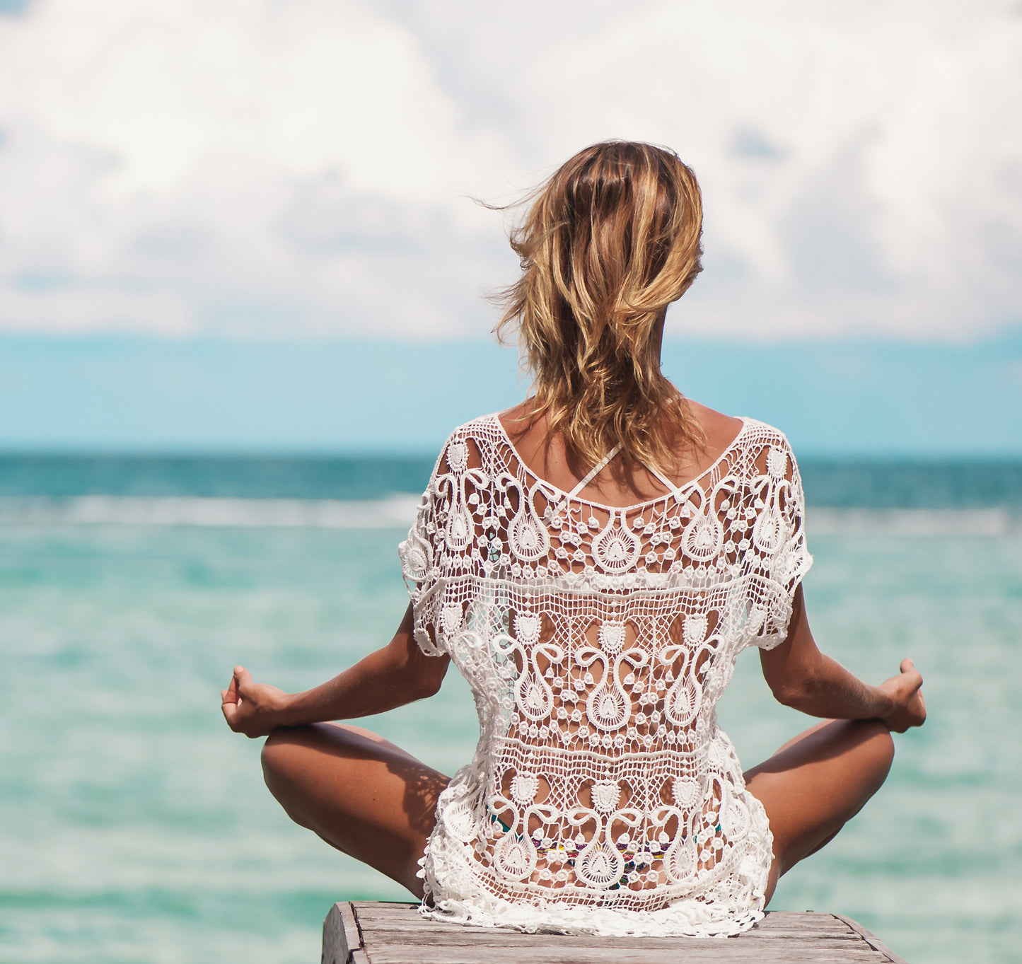 woman sitting on beach doing yoga